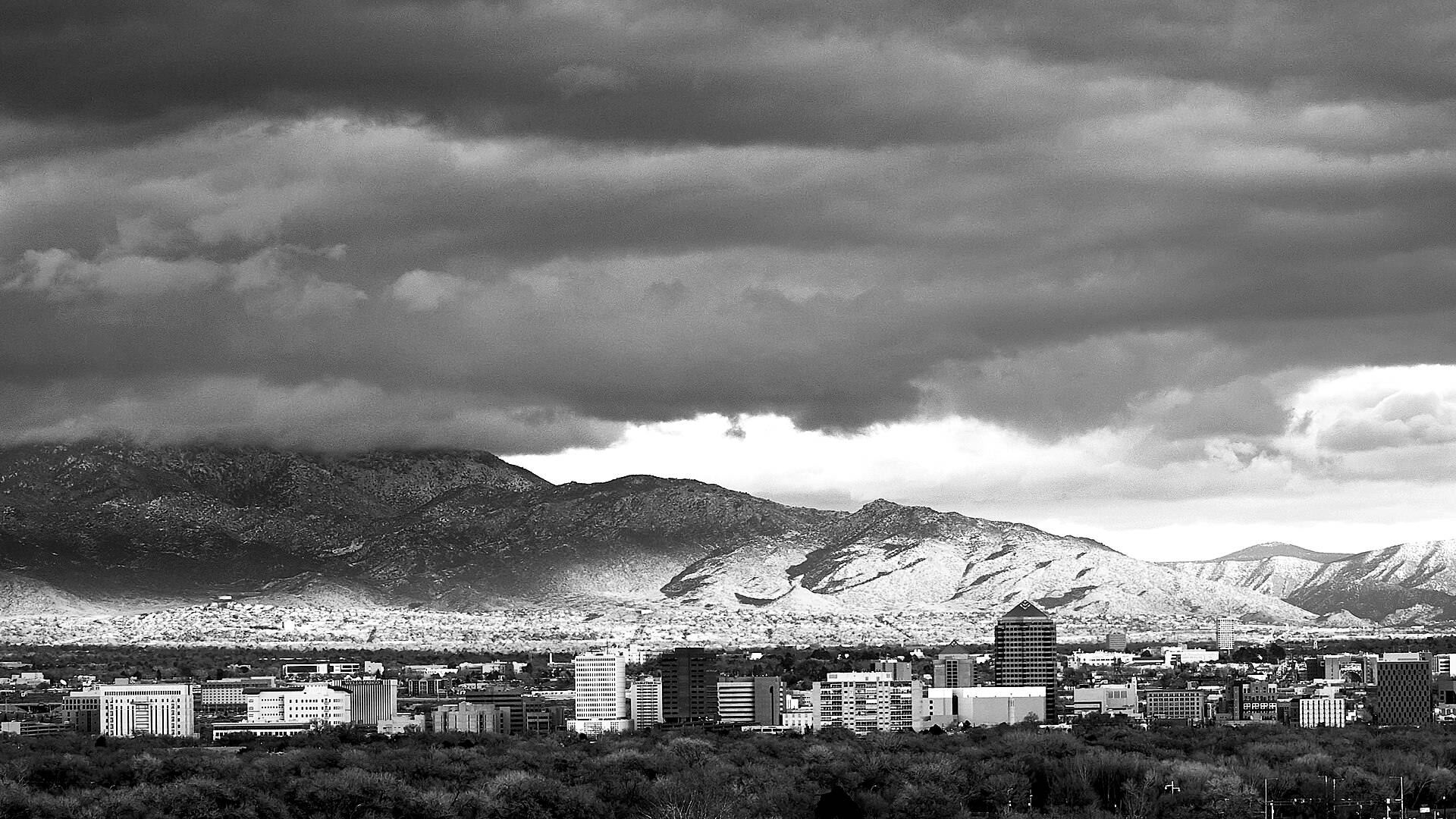 Downtown Albuquerque under storm clouds with the Sandia Mountains behind